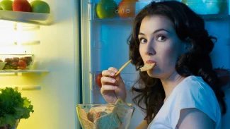 Žena stojící v noci u otevřené ledničky