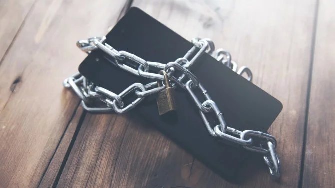 mobilní telefon na dřevěném stole, řetěz a zámek