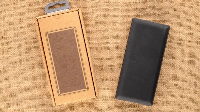 Jedna nová černá přenosná baterie v papírovém obalu na jutovém plátně, makro, pohled shora.