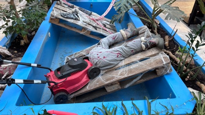 Detail na halloweenskou dekoraci v podobě figuríny pod sekačkou na trávě