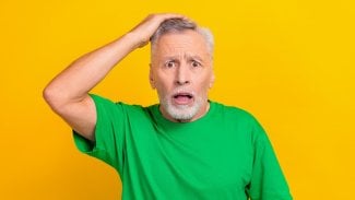 Senior stojí se zděšeným výrazem s otevřenými ústy a s rukou na hlavě