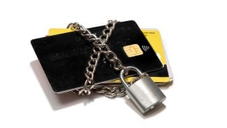 Platební karty omotané řetězem a zamčené na zámek.