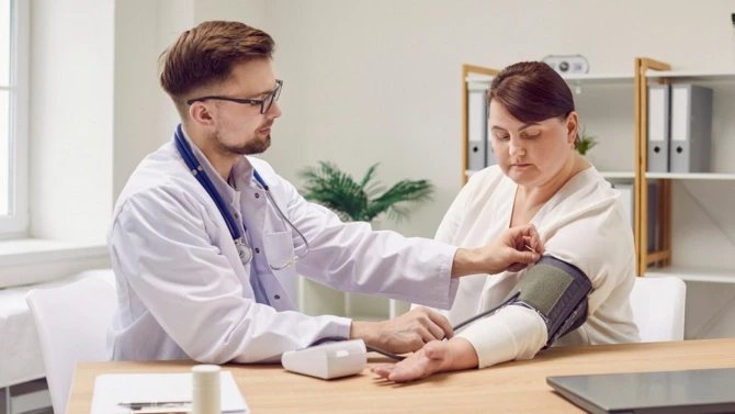 Lékař měří tlak obézní pacientce