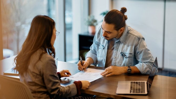 Mladý muž (cizinec) podepisuje v kanceláři smlouvu
