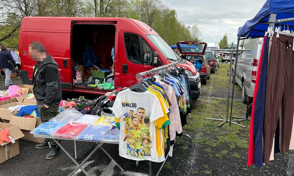 Fotky zaznamenávají kontrolu celníků na bleším trhu, kde odhalili prodejce padělků sportovních dresů