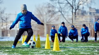Kluci hrají v zimě na trávníku fotbal