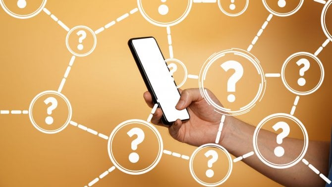 Koncept často kladených otázek (FAQ). Mužská ruka ukazující prázdnou bílou obrazovku moderního smartphonu. Otazníky s osobou držící černý smartphone.