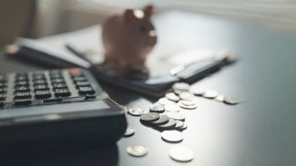 Kalkulačka a mince rozházené po stole.