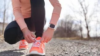 žena ve sportovním oděvu si zavazuje tkaničky na běžeckých teniskách