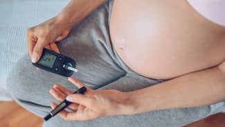 Detail břicha těhotné ženy, která používá glukometr