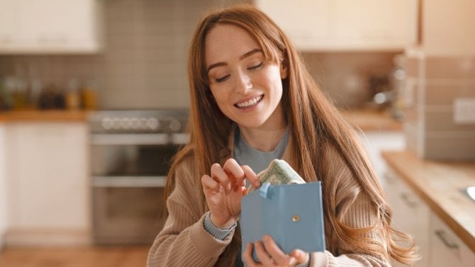 Hezká žena v kuchyni počítá peníze v peněžence