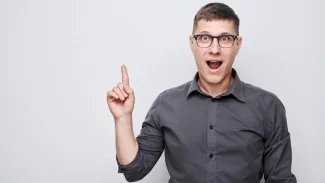 Muž s otevřenou pusou a zvednutým ukazováčkem.