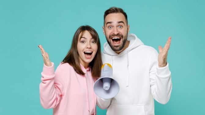 Mladý muž a žena sdělují radostně novinku pomocí hlásné trouby