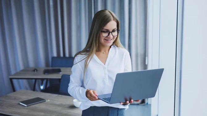 Stojící žena v kanceláři drží notebook