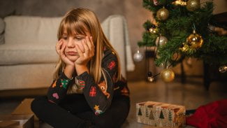 Malá dívka je smutná u vánočního stromečku