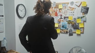 Žena telefonuje a stojí před policejní nástěnkou.