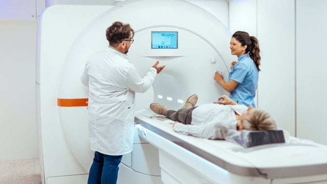 Dva zdravotníci vyšetřují ženu magnetickou rezonancí