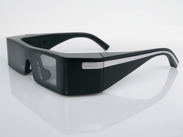 Chytré brýle Lumus na rozdíl od konkurence nepoužívají jeden "promítač", nýbrž rovnou dva. Proto dokáží obrazem vyplnit celé zorné pole. V současnosti je k dispozici vývojová verze, která však nevypadá tak elegantně, jako ta na obrázku.