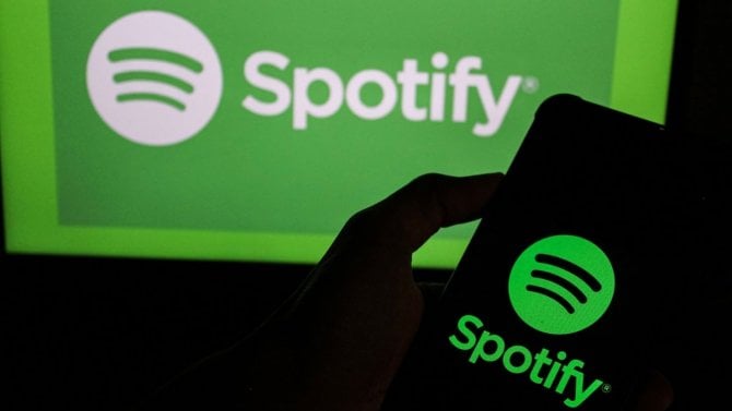Na této fotografické ilustraci je logo Spotify zobrazeno na smartphonu s logem Spotify Music na pozadí.