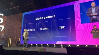 muž na podiu AWS Cloud day, v pozadí loga mediálních partnerů