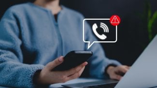 Žena drží v ruce telefon s upozorněním na podvod.