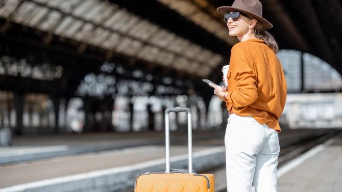 Žena s kufrem na vlakovém nádraží