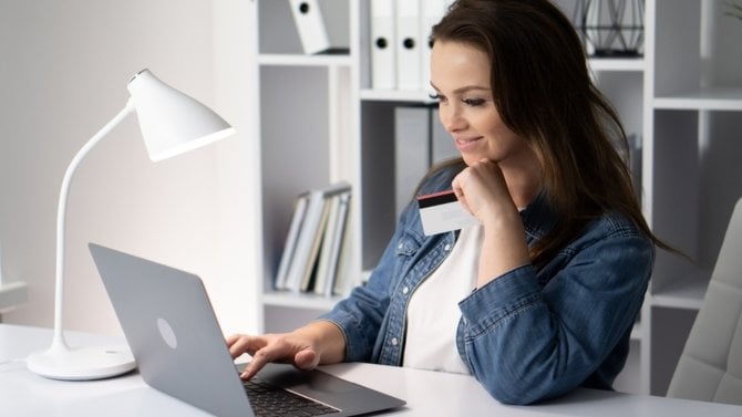 Mladá žena s radostí nakupuje a platí na e-shopu (u počítače)
