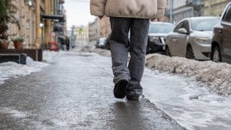 Chodec jde po zamrzlém chodníku.