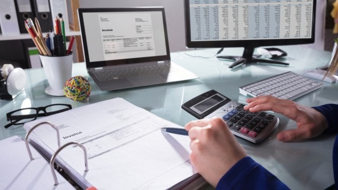 Podnikatel počítá v kanceláři a má u toho faktury