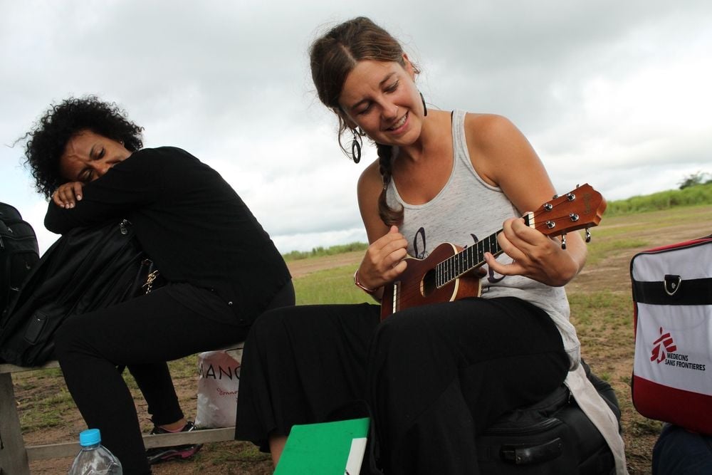 Zdravotní sestra Lékařů bez hranic, která pracovala v projektu zaměřeném na léčbu eboly v Guinei a Libérii, si zkracuje čekání na svůj odvoz hrou na ukulele.