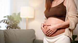 Těhotná žena, detail na břicho, které si objímá rukama