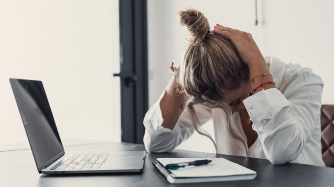 Stresovaná, unavená žena trpící silnými bolestmi hlavy po práci na notebooku, vyčerpaná dívka trpící chronickými migrénami, která si masíruje spánky, aby zmírnila bolest hlavy.