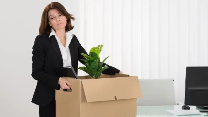 Smutná zaměstnankyně odnášející osobní věci z kanceláře v krabici