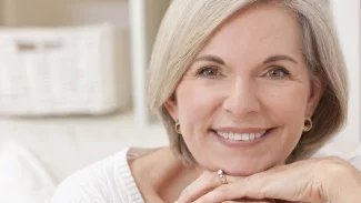 Krásná seniorka s milým úsměvem, opírá si rukou bradu