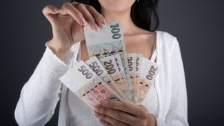 Detail ženiných rukou, jak drží stokorunové a dvousetkorunové bankovky