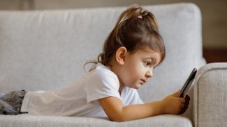 Malá dívka hledí upřeně na displej tabletu