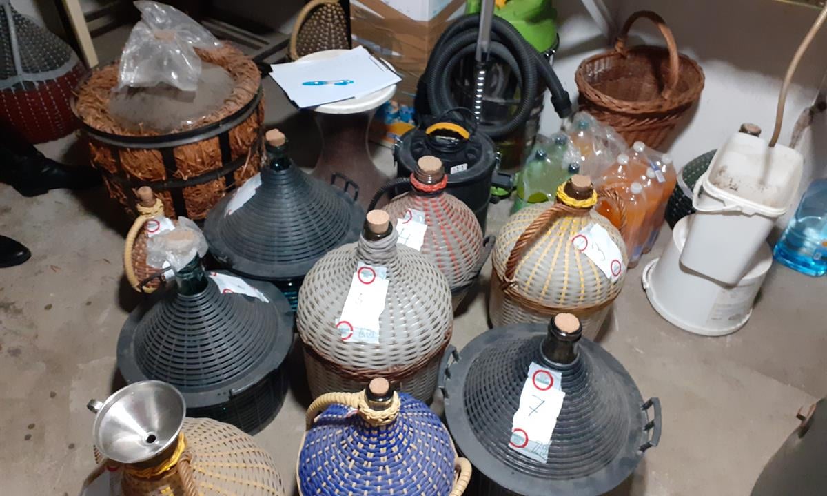 Na obrázku jsou vyobrazeny demižony postavené v místnosti