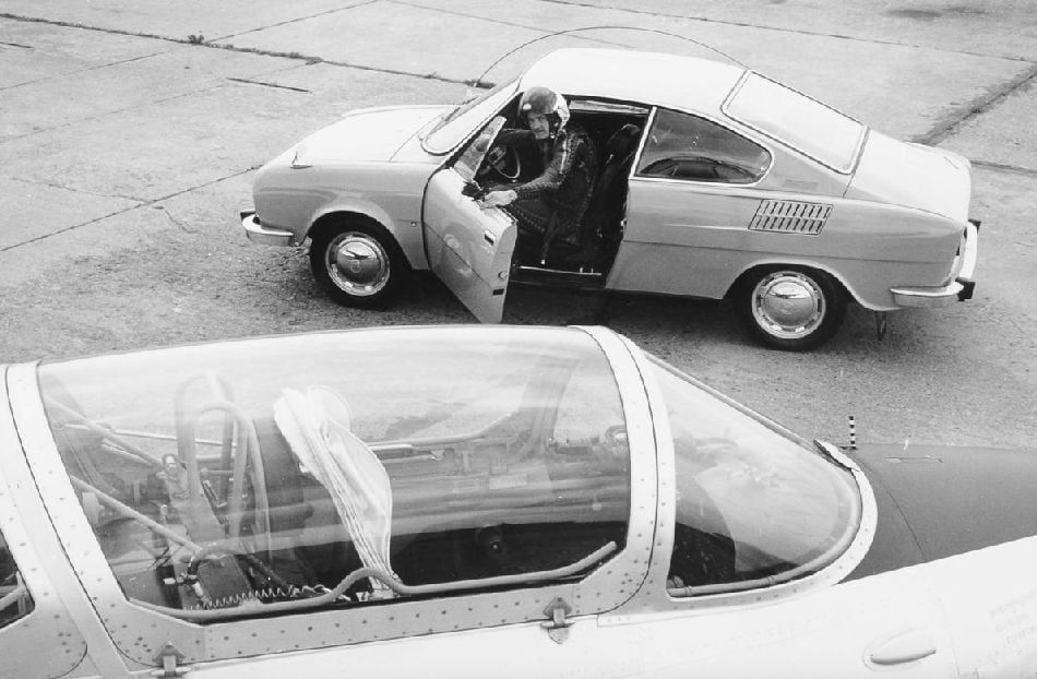 Pilot vystupuje z kupátka s ochrannou přilbou na hlavě. Jakpak by se mu asi cestovalo v poměrně nízkém vozidle?