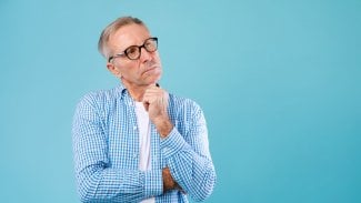 Starší muž stojí se zamyšleným výrazem a kouká vzhůru