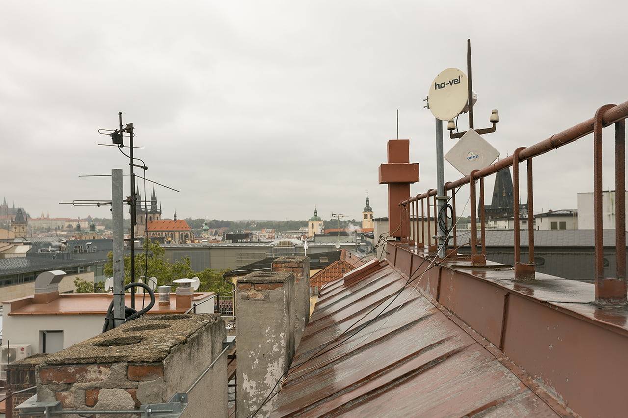 Antény jsou schované v červeném kříži na střeše budovy. Senovážné náměstí, Praha.