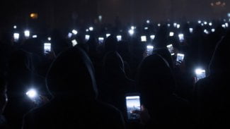 Dav temných postav držících svítící mobilní telefony