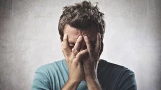 Mladý muž si drží obličej v rukách a tváří se zoufale