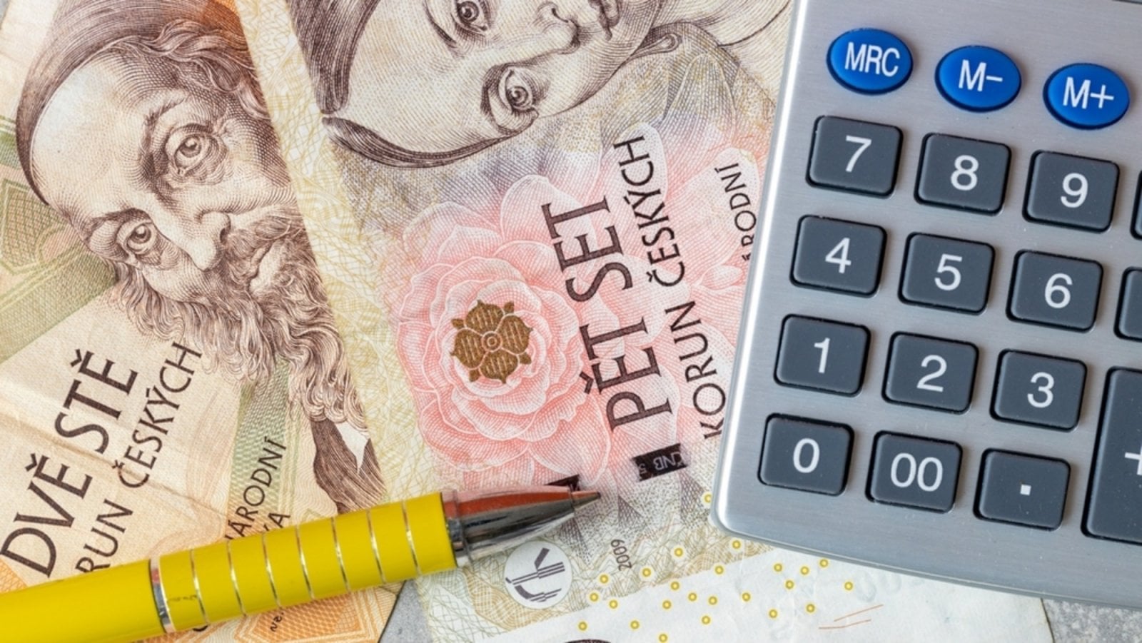 České peníze, kalkulačka a propiska na stole