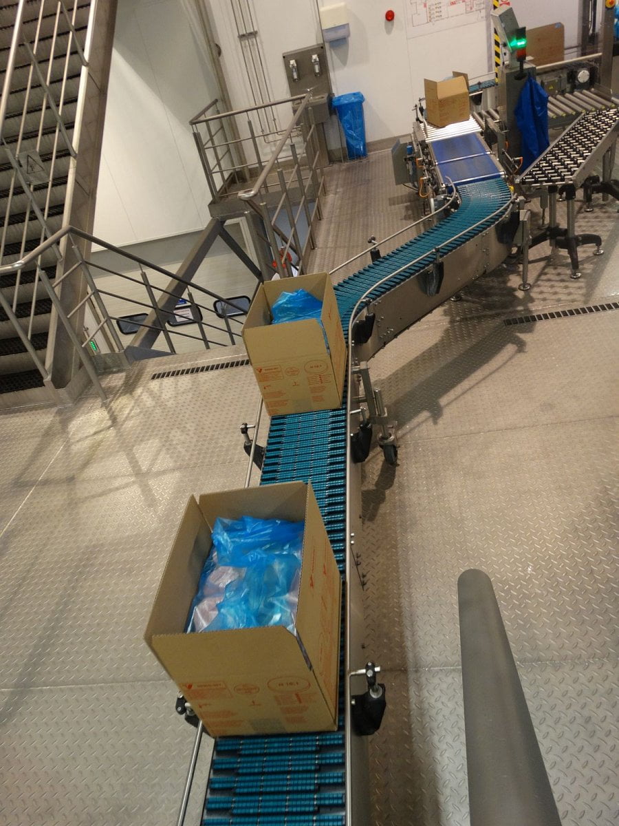 Naplněné krabice putují po pásu ke stroji, který je zalepí