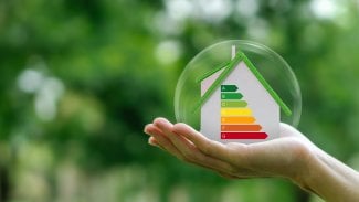 Ruka držící v bublině maketu domu s energetickým štítkem.