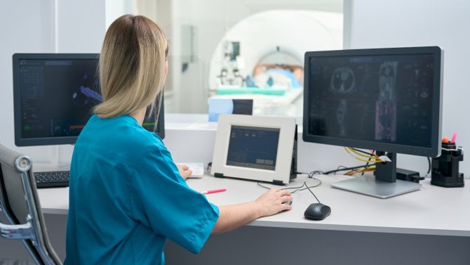 Radioložka vyšetřuje pacienta na tomografu