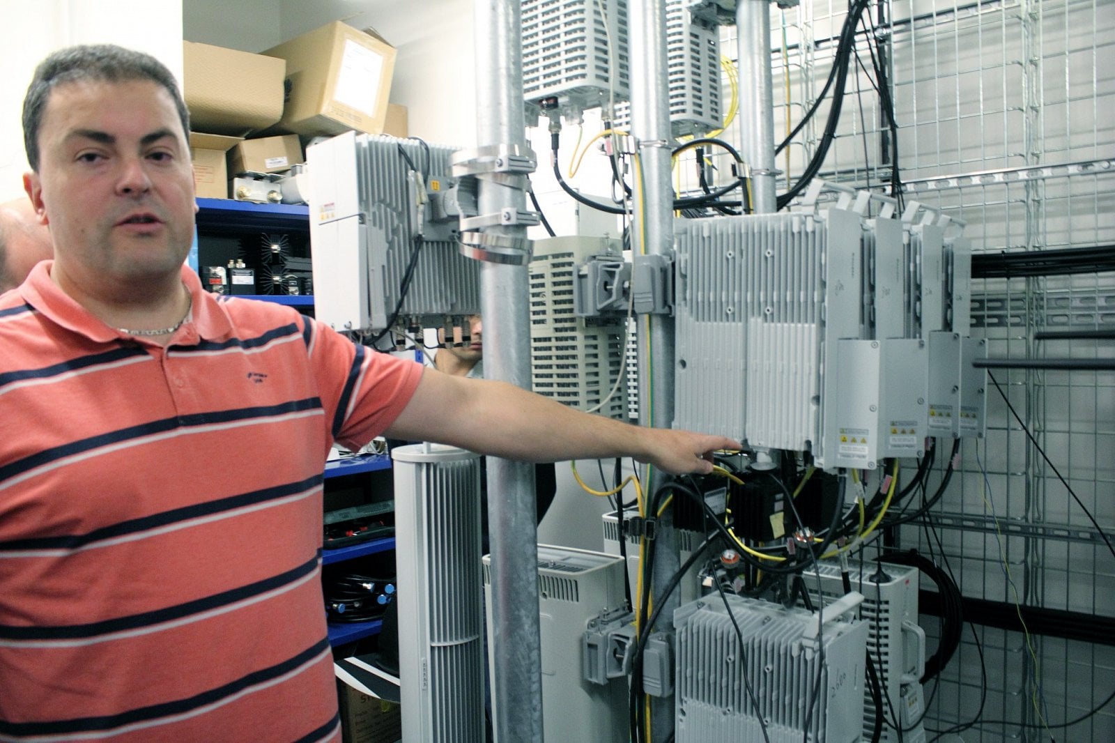 Toto jsou vysílací jednotky. "Jsou to standardní rádiové jednotky, které jsou na vysílačích. Mají dva výstupy, takže aby to bylo 4x4 MIMO, máme je zdvojené. Dvě jednotky pro pásmo 800 Mhz, za nim dvě jednotky pro pásmo 2100 Mhz, nahoře je pásmo 1800 Mhz. Jedinou výjimkou je dole rovnou 'čtyřvýfuková' jednotka pro pásmo 2600 Mhz," ukazuje Byrtus. "V síti už několik 2600 sektorů máme, hlavně v Karlových Varech, a tam už máme jednotky rovnou v konfiguraci 4x4 MIMO. Bohužel zatím není komerční zařízení, které by to dokázalo využít," doplňuje.