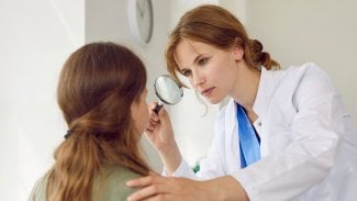 Mladá hezká lékařka vyšetřuje krk mladistvé dívce