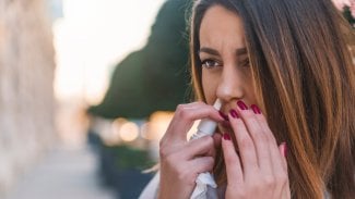 Žena s rýmou si aplikuje do nosu sprej