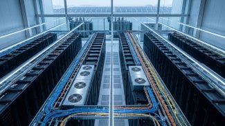 Řady serverových racků v datovém centru s chladicími jednotkami a optickými kabely, v pozadí energetická infrastruktura symbolizující technologické zázemí umělé inteligence.